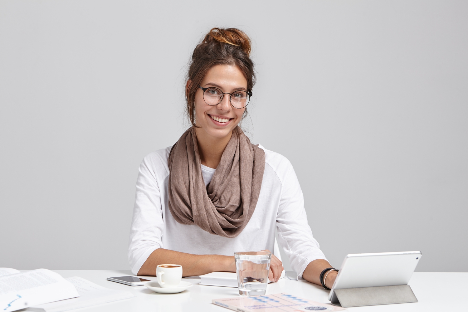 Cute female blogger types new interesting post at tablet, uses high speed internet connection, has confident and happy look, sits at work place alone. Elegant female lady makes financial report